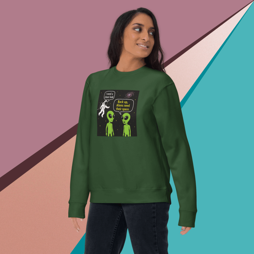 Woman wearing a green sweatshirt with an alien design and text.