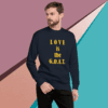 unisex-premium-sweatshirt-navy-blazer-front-68f061351f091 Man wearing a black sweatshirt with "LOVE is the G.O.A.T." printed in gold.