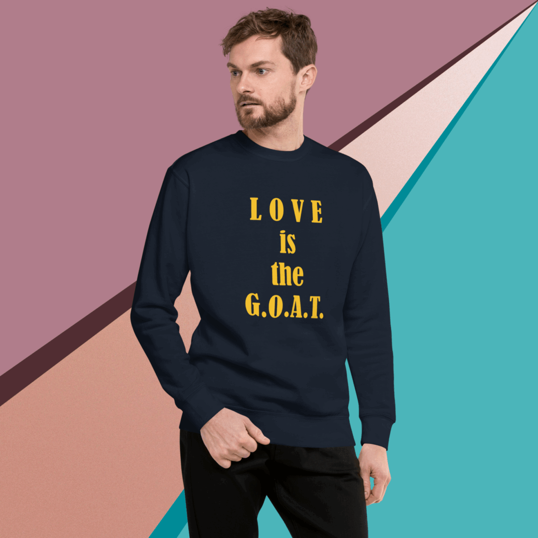 unisex-premium-sweatshirt-navy-blazer-front-68f061351f091 Man wearing a black sweatshirt with "LOVE is the G.O.A.T." printed in gold.