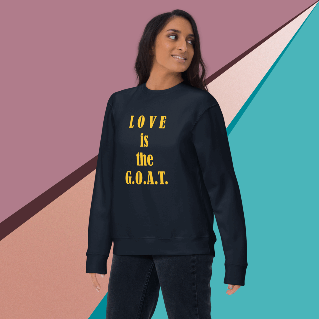 unisex-premium-sweatshirt-navy-blazer-front-68f061abc7e68 Woman wearing a black sweatshirt with the phrase 'LOVE IS the G.O.A.T.'