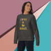 unisex-premium-sweatshirt-vintage-black-front-68f061abcb491 Smiling woman wearing a sweatshirt that says 'LOVE IS the G.O.A.T.'