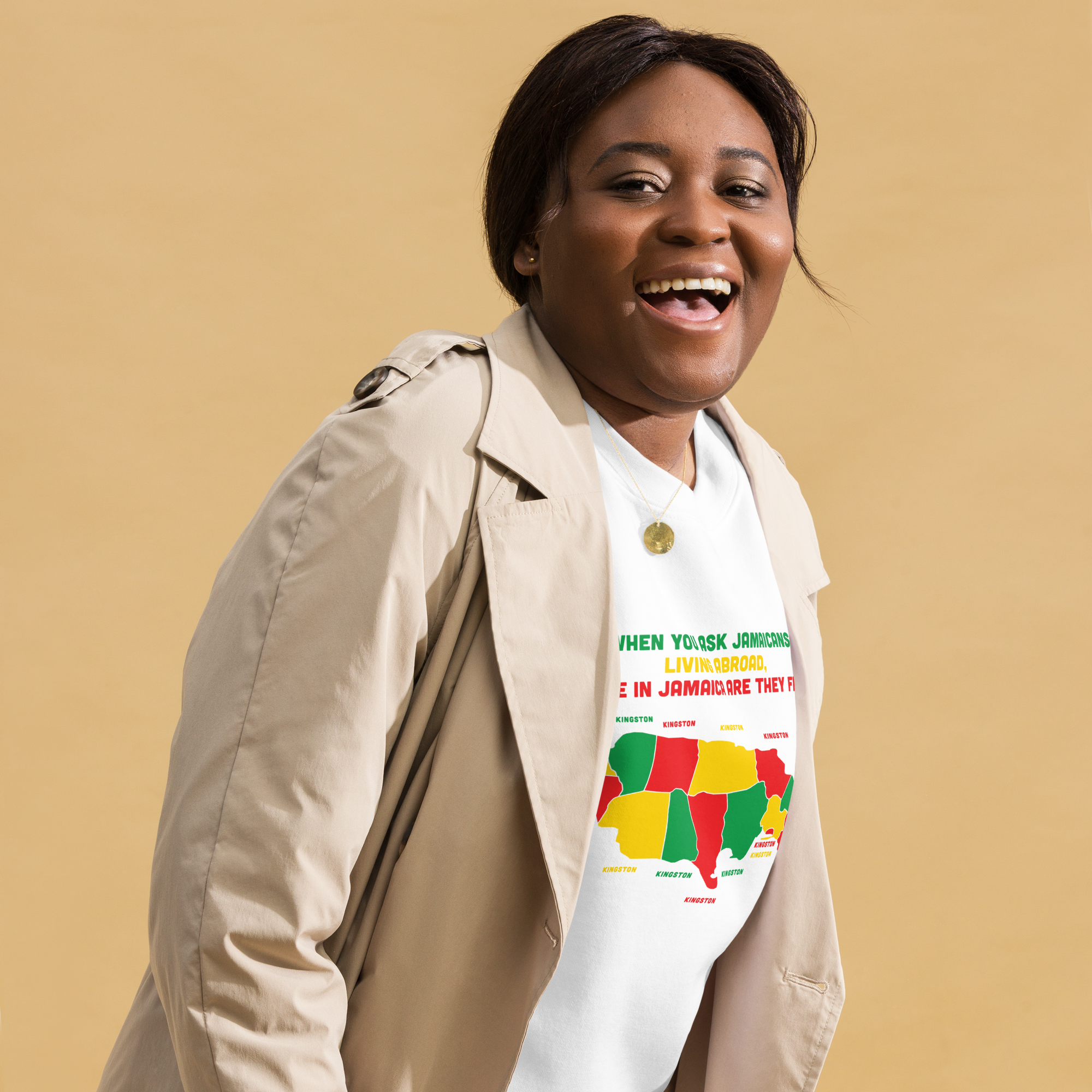 Smiling woman wearing a colorful Jamaican-themed t-shirt and beige coat.