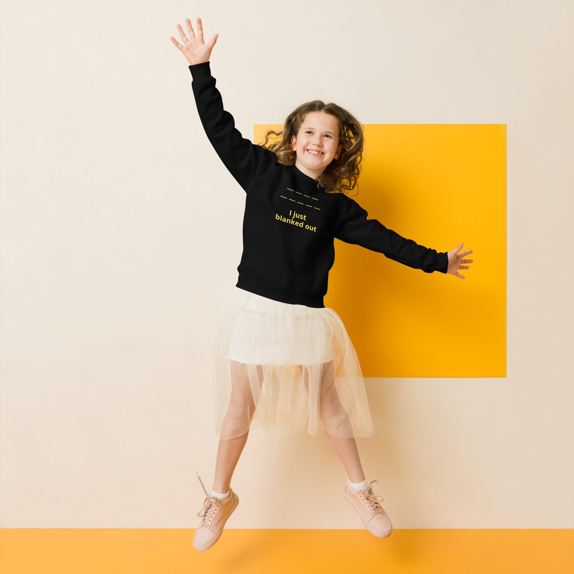 Joyful girl jumping with arms raised, wearing a black sweatshirt and white skirt.
