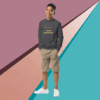 Young man wearing a dark sweatshirt and khaki shorts stands against a colorful geometric background.