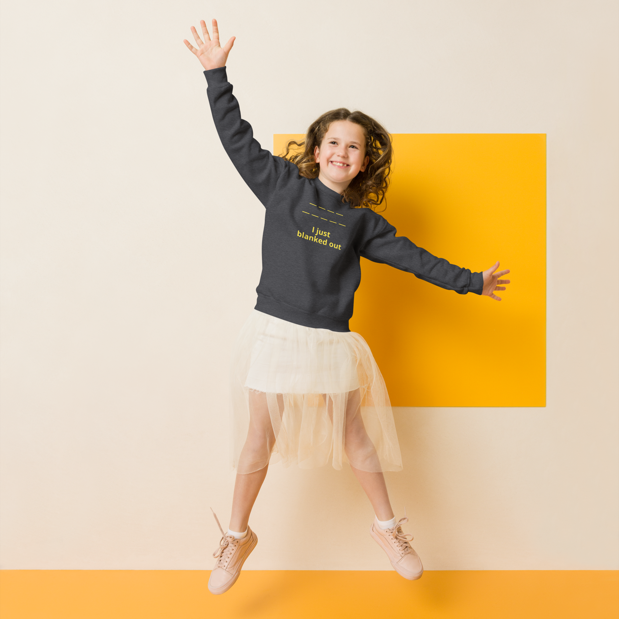 Joyful girl jumping with arms raised, wearing a sweatshirt and tulle skirt.