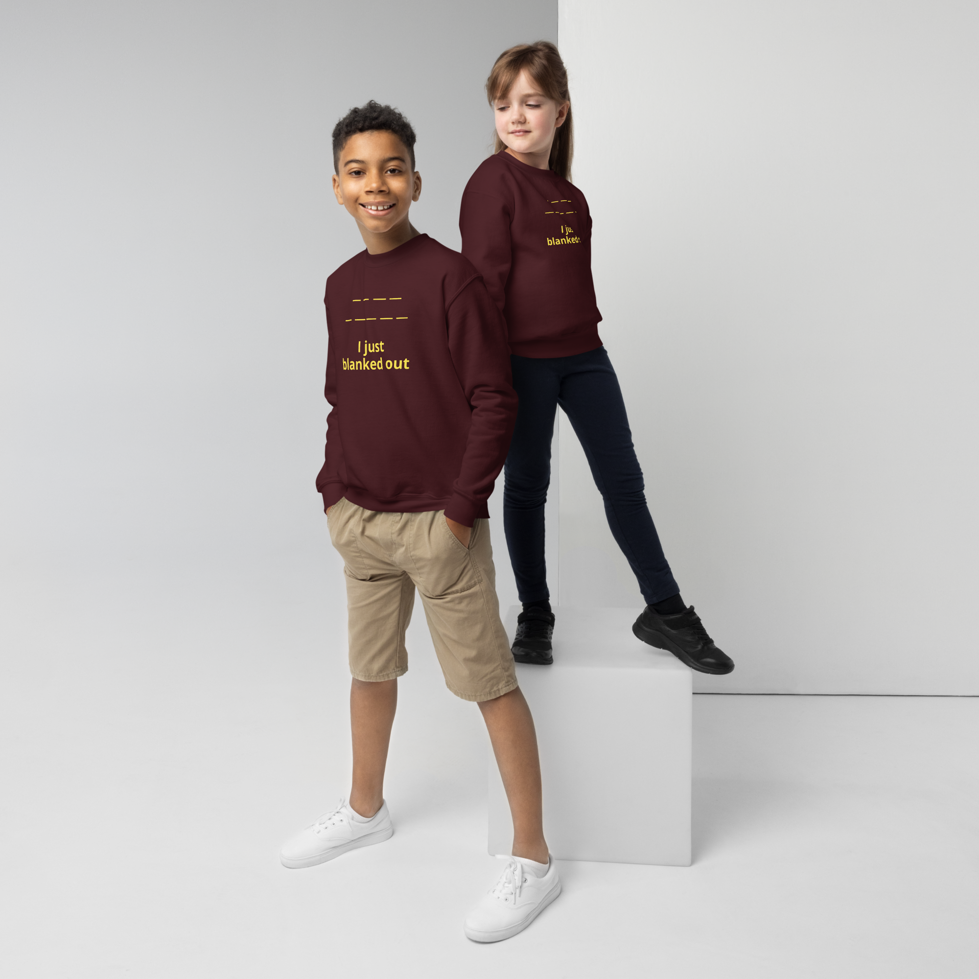 Two kids wearing matching maroon sweatshirts with yellow text.