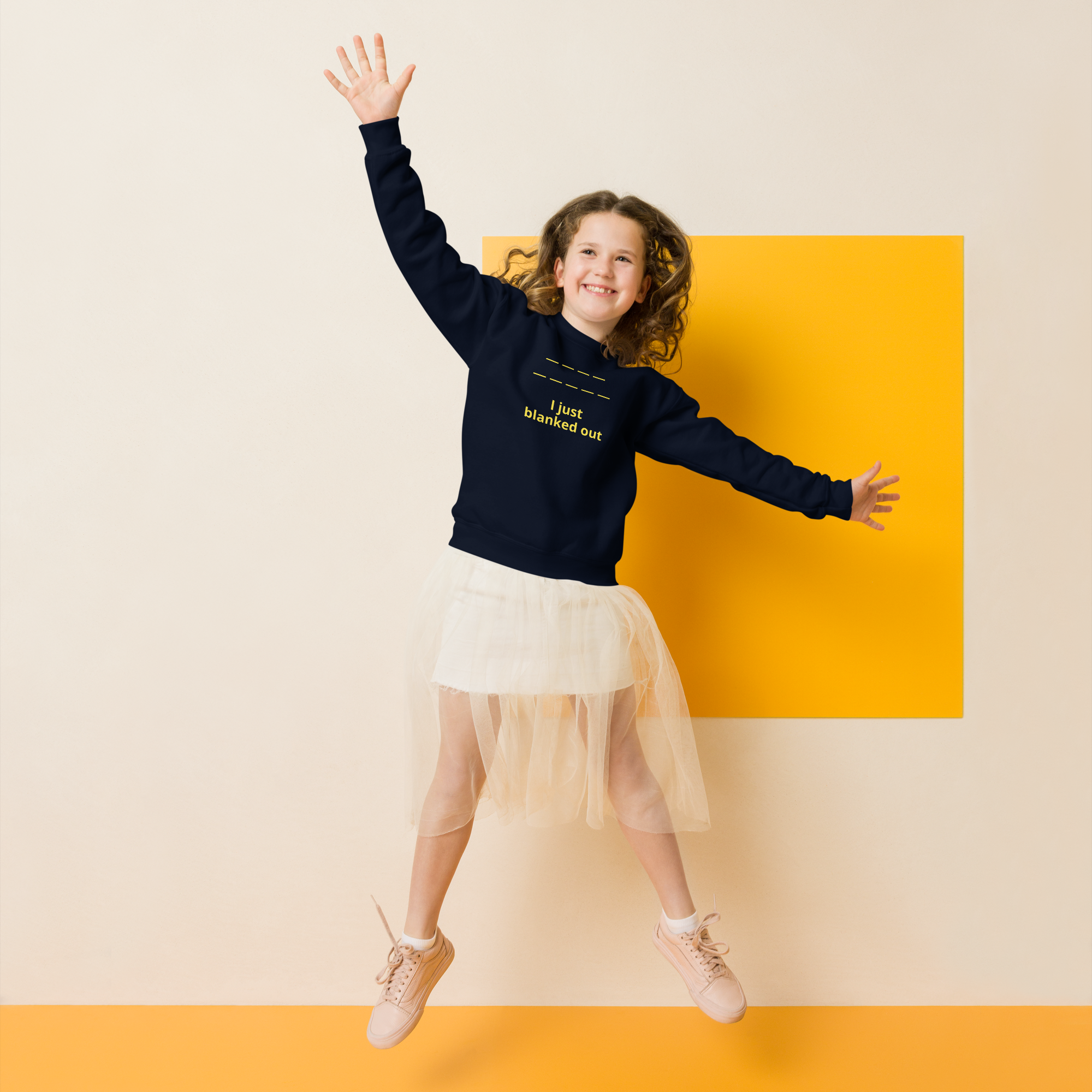A joyful girl jumps with arms outstretched, wearing a navy sweatshirt and white skirt.