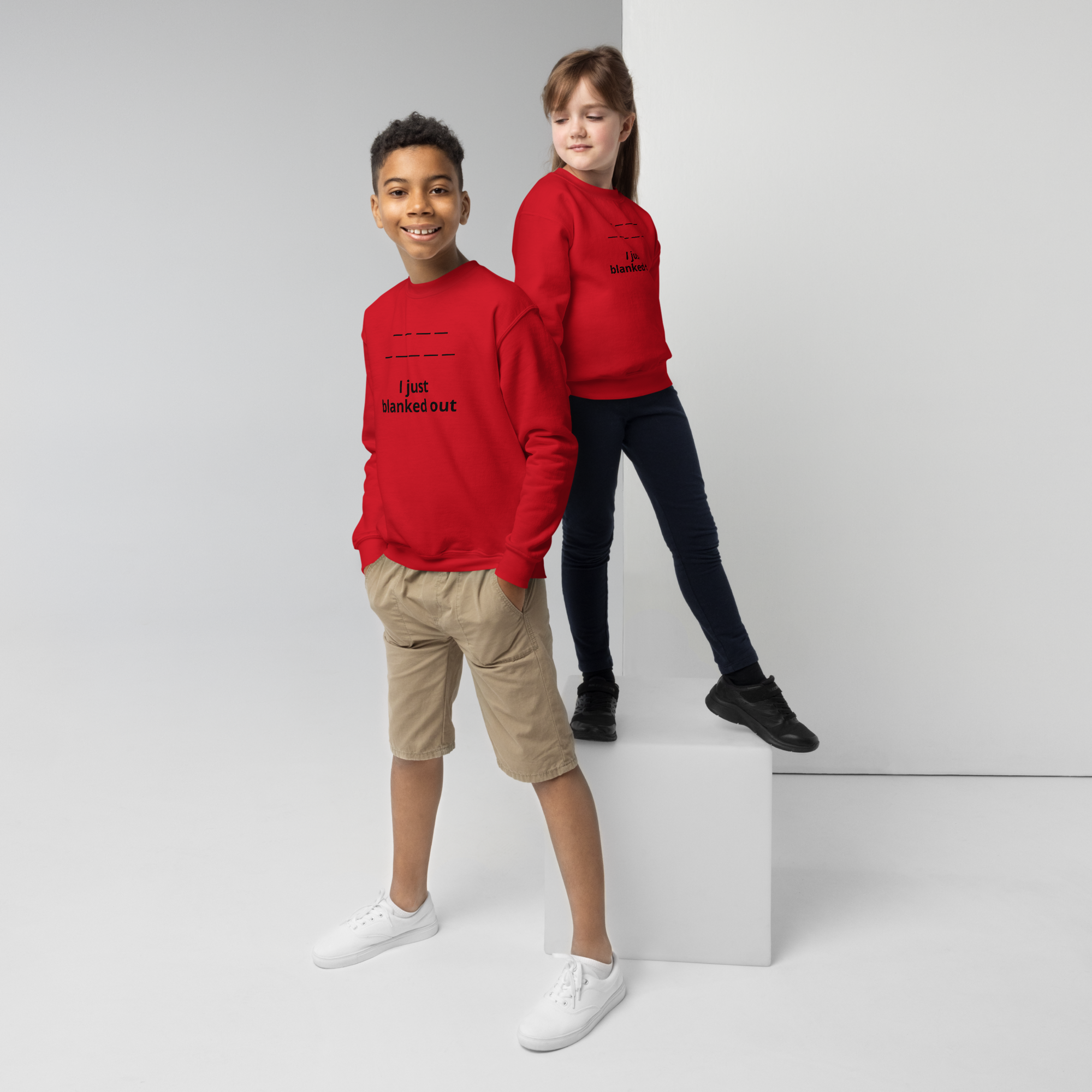 Two children wearing red sweatshirts with "I just blanked out" text, posing against a white backdrop.