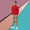 Young man in a red sweatshirt and beige shorts standing against a colorful geometric background.