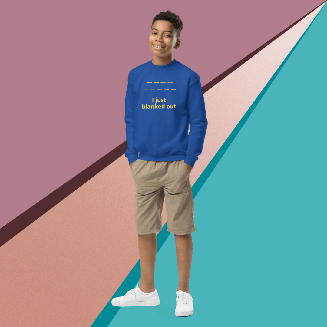 Young man in blue sweatshirt and beige shorts stands against colorful geometric background.