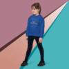 A young girl in a blue sweatshirt and black pants poses against a colorful geometric background.