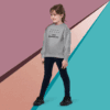 Young girl in a gray sweatshirt and black pants posing against a colorful geometric background.