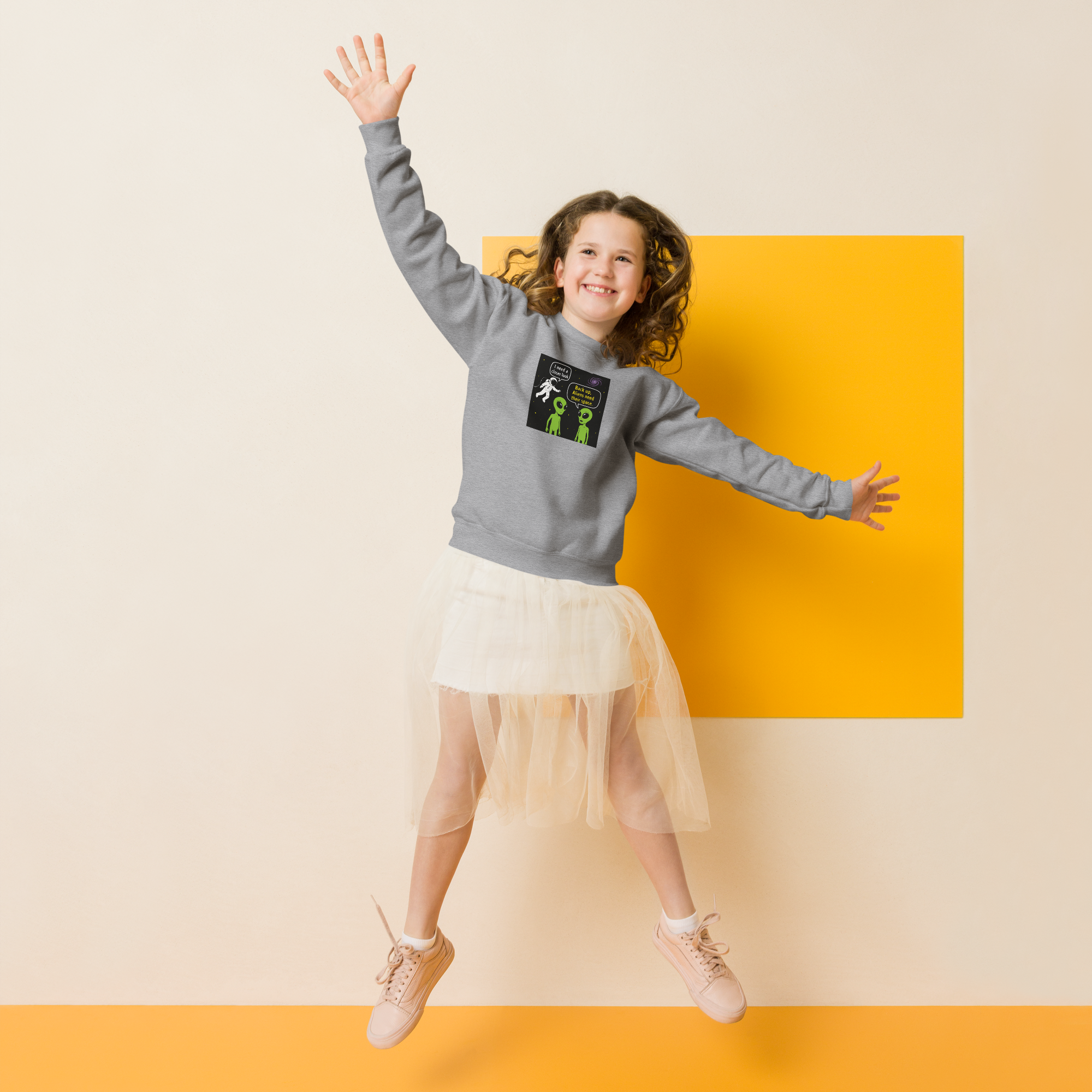 Happy girl in a grey sweatshirt with alien print jumping joyfully.