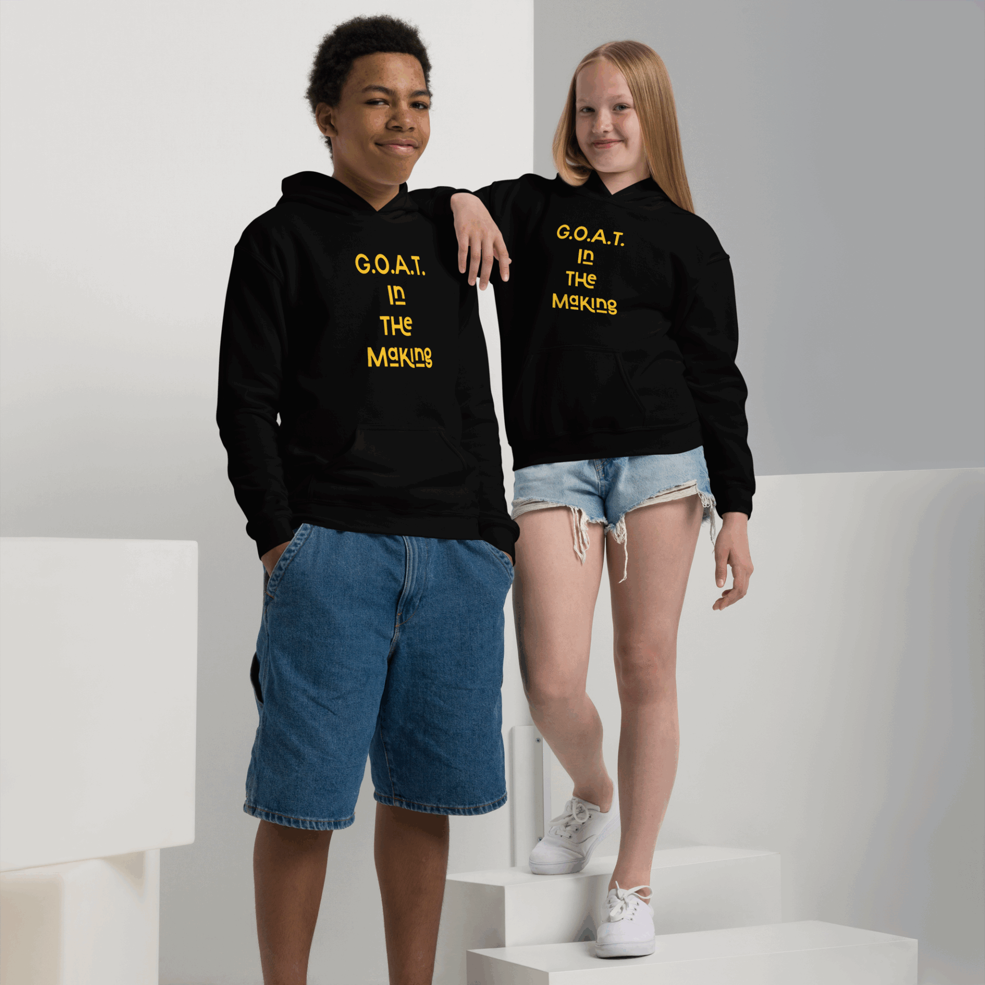 Two young models wearing black hoodies with yellow text, paired with casual shorts.
