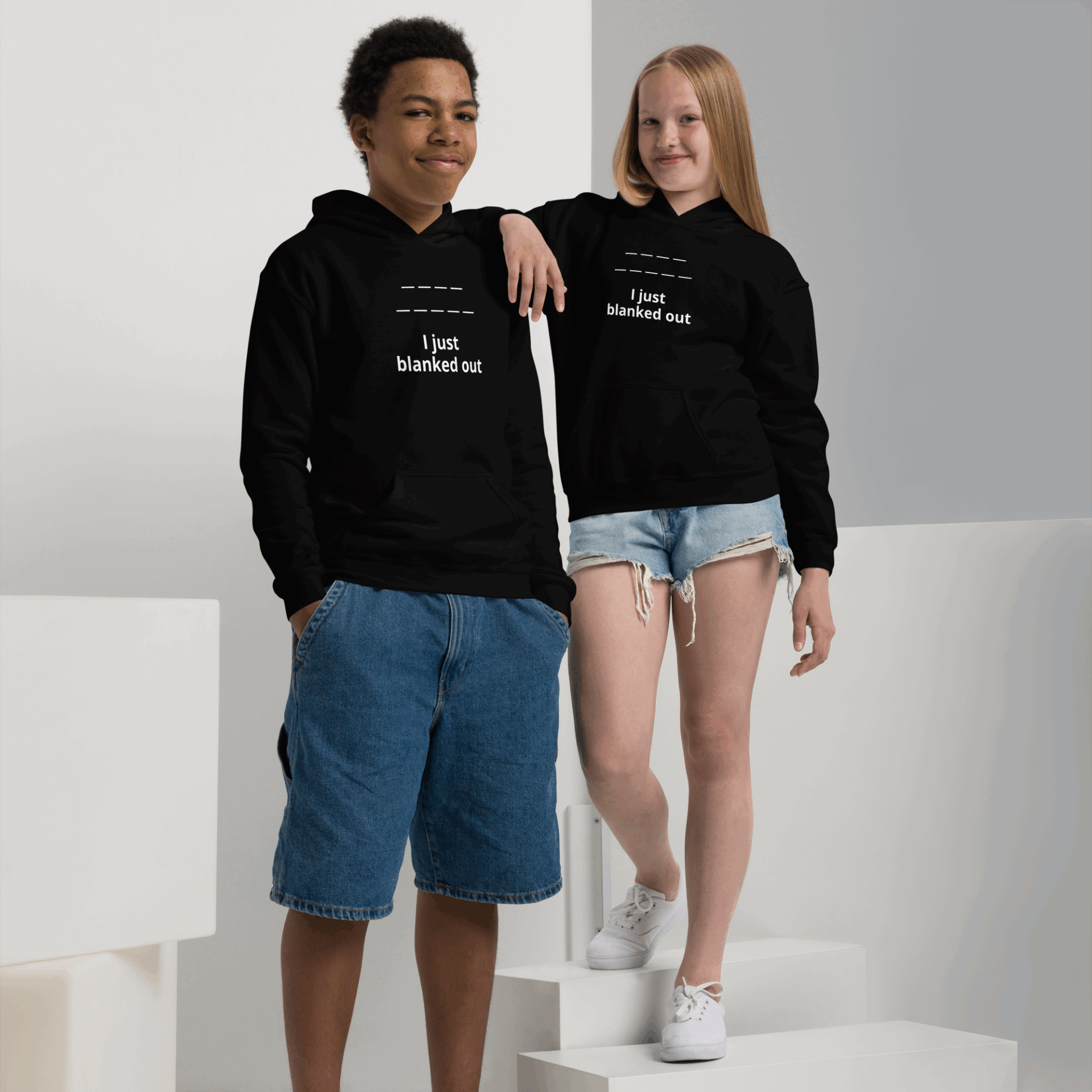 Two young adults wearing matching black hoodies with white text, posing confidently.