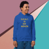 Young man wearing a blue hoodie with "G.O.A.T IS THE MISSING" text.