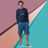 A man in a navy sweatshirt and blue shorts stands against a colorful geometric background.