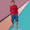 Smiling man in red sweater and blue shorts against colorful geometric background.